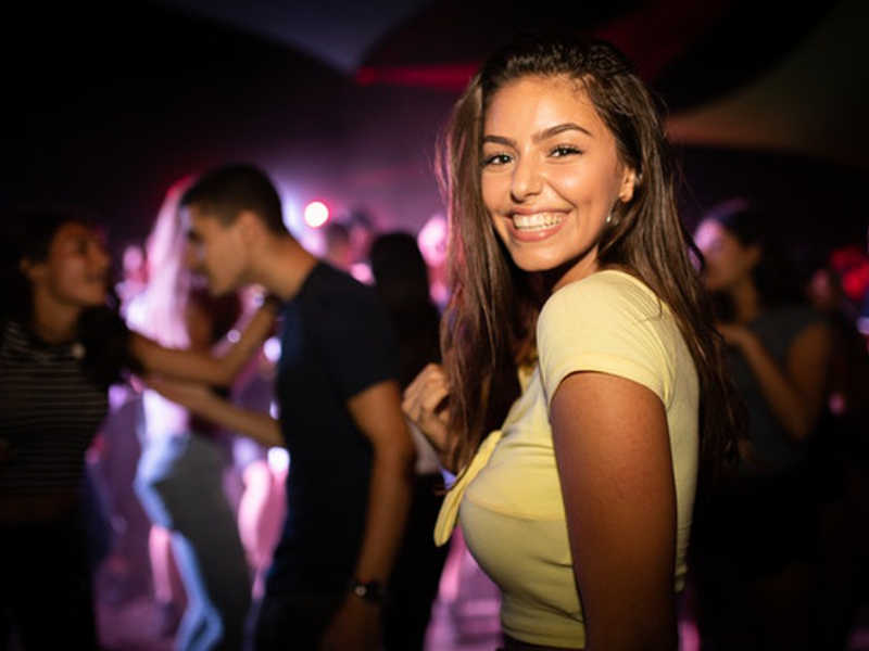 woman smiling at club with many people dancing out of focus