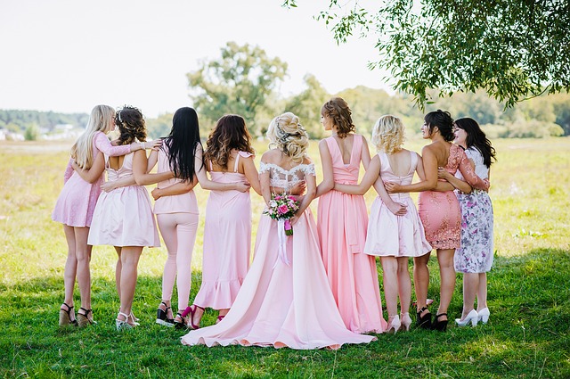 9 women standing in a field wearing pink dreses